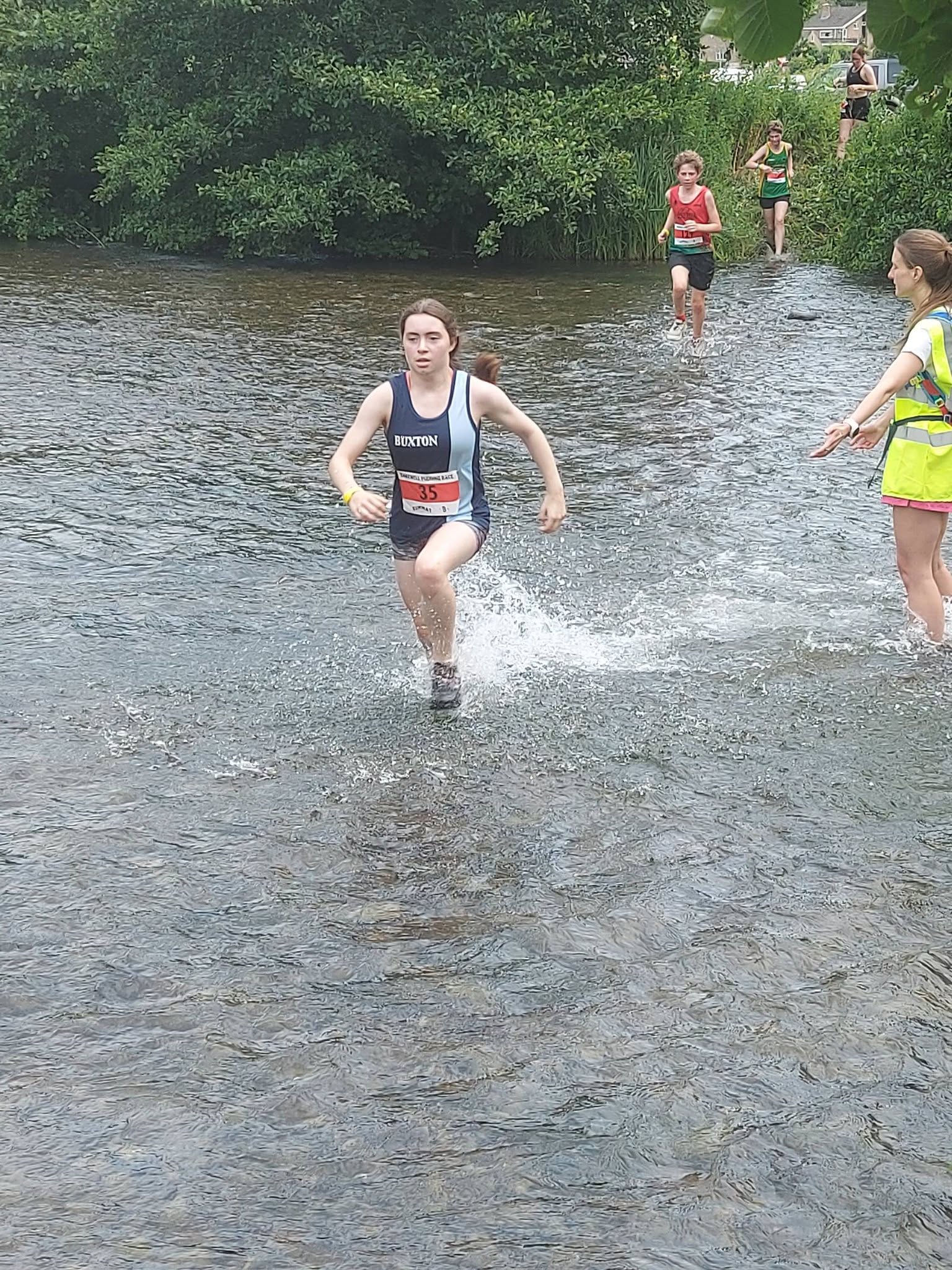 A Buxton AC junior athlete running through a river