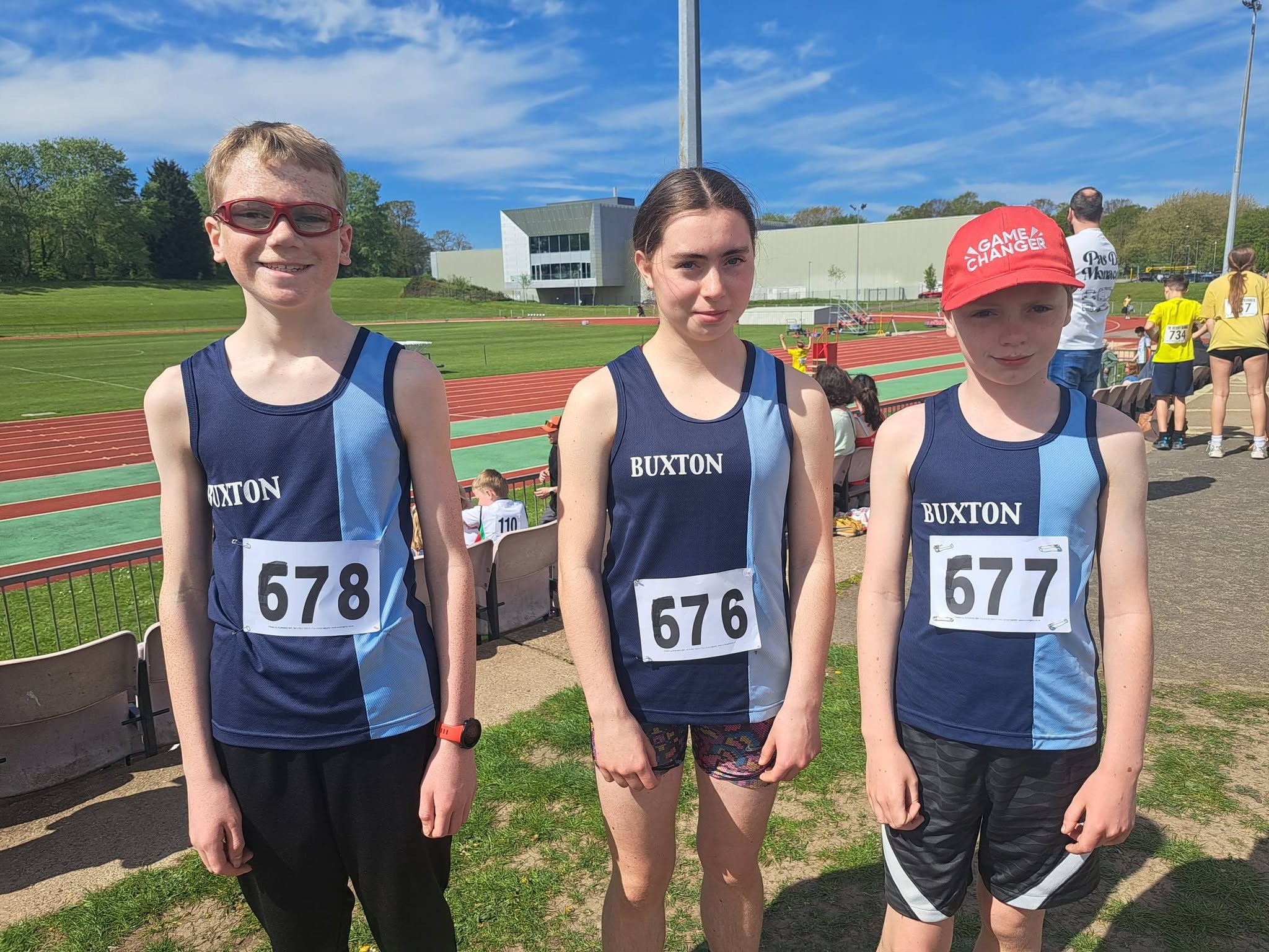 Three Buxton AC junior athletes at an athletics track